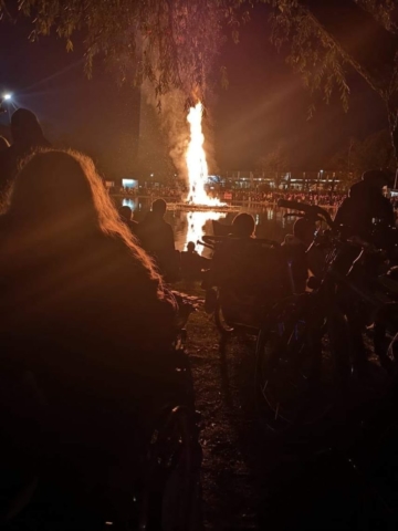 Der Wicker Man brennt lichterloh.  Zuschauer beobachten ihn vom Seeufer